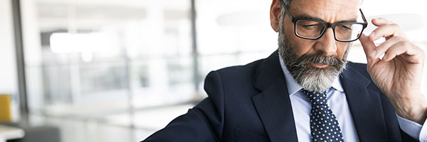 Cuentas Banca Privada - Asesor financiero con traje, corbata y gafas mirando una tablet sentado en una silla en la oficina