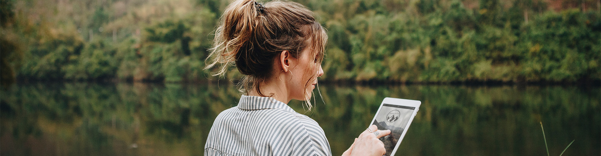 Préstamo Joven In - Una mujer usando una tableta digital en plena naturaleza Préstamo Joven In - Una mujer usando una tableta digital en plena naturaleza