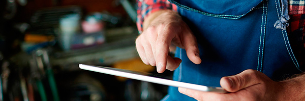 Cobros Autónomos - Un hombre con camisa de cuadros está utilizando su tableta digital. Cobros Autónomos - Un hombre con camisa de cuadros está utilizando su tableta digital.