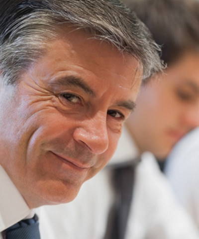 Subvenciones y ayudas - Ejecutivo sonriendo en una reunión Subvenciones y ayudas - Ejecutivo sonriendo en una reunión