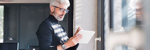 Dibisa Kontua hombre-negocios-maduro-camiseta-negra-gafas-con-tablet-en-oficina-junto-ventana