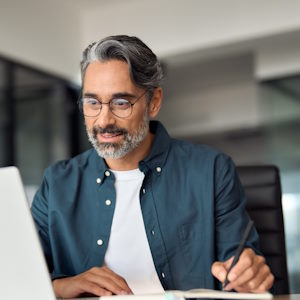 Hombre tomando notas de un portatil