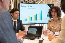 personas reunidas en despacho con pantalla de fondo con graficos