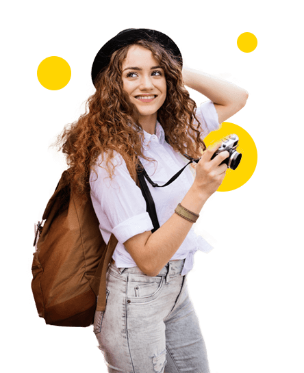 Momento Viajar al extranjero - Público millenial chica sonriendo con cámara de fotos y mochila - Caja Rural de Navarra Momento Viajar al extranjero - Público millenial chica sonriendo con cámara de fotos y mochila - Caja Rural de Navarra