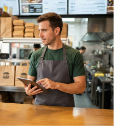 Chico joven con una tablet atendiendo en su comercio