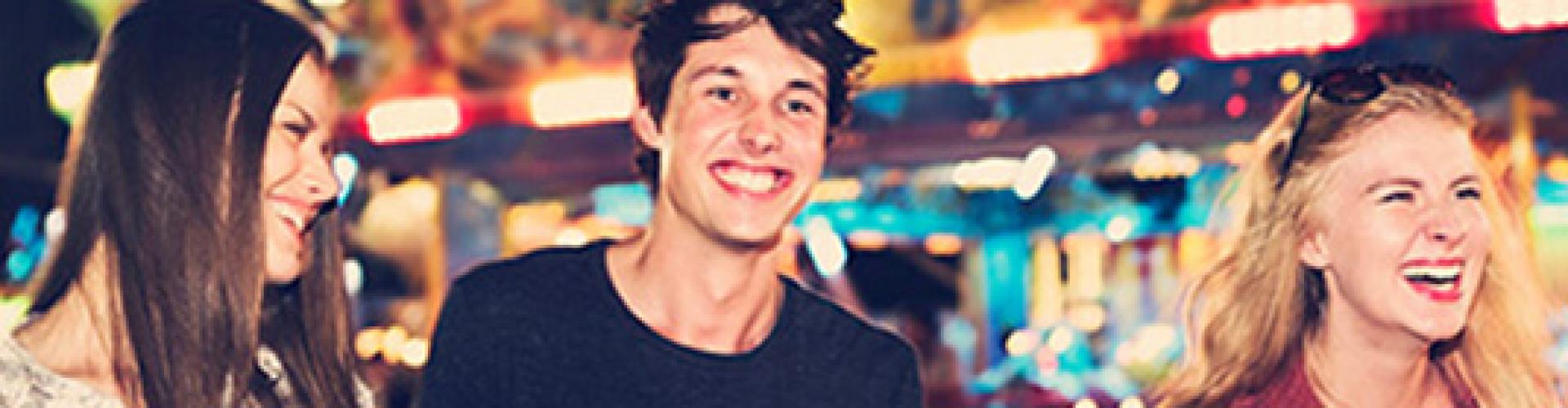 Tarjeta Joven IN - Chico con dos chicas en una feria sonriendo
