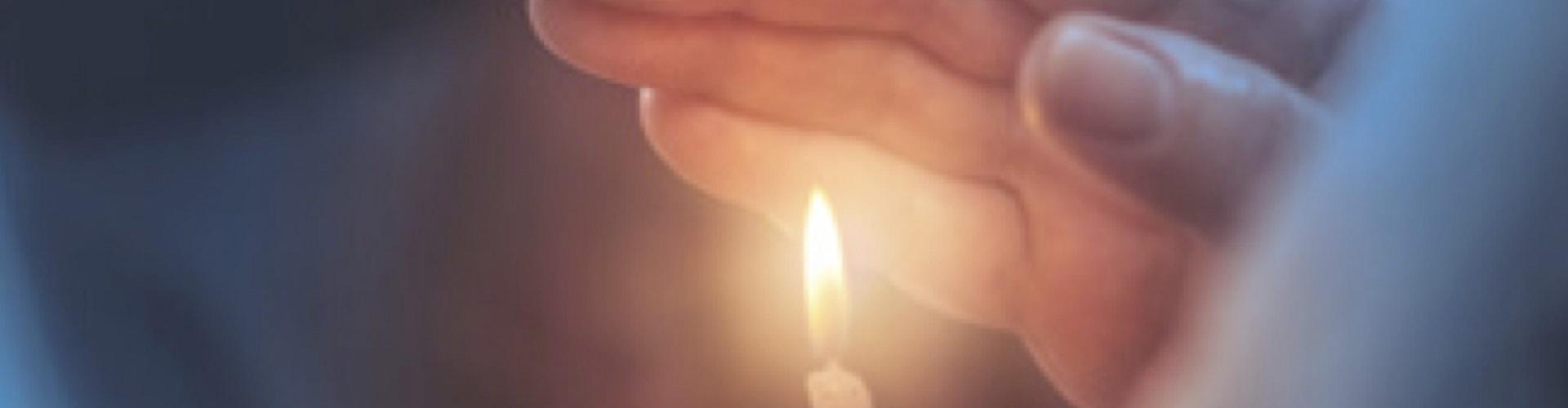 Soluciones Entidades Religiosas cabecera - Mano agarrando una vela encendida - Caja Rural de Navarra