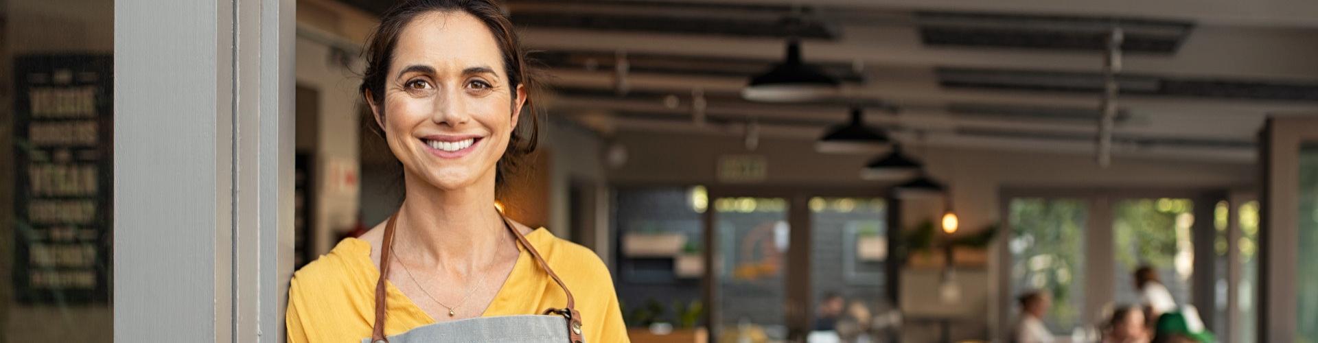 financiación autónomos - mujer sonriendo frente a su negocio - Caja Rural de Navarra