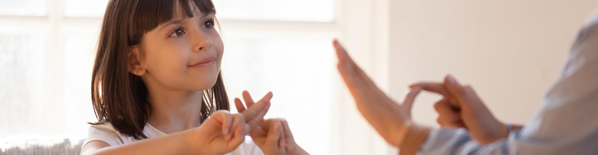 madre comunicandose con su hija sorda foco en la niña hablando con leguaje de signos