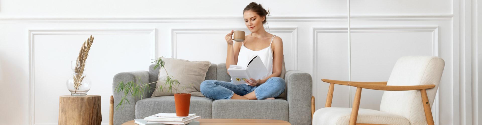 chica joven relajada leyendo libro en el sofa de su casa