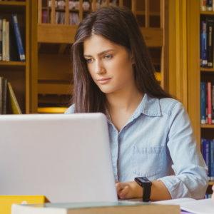 Crear tu currículum con Caja Rural de Navarra - Mujer morena en la biblioteca rellenando su currículum en su portátil Crear tu currículum con Caja Rural de Navarra - Mujer morena en la biblioteca rellenando su currículum en su portátil