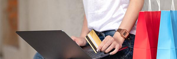 Servicio de Aplazamiento de pago para Particulares - Una chica, de compras, tiene en la mano una tarjeta de crédito Servicio de Aplazamiento de pago para Particulares - Una chica, de compras, tiene en la mano una tarjeta de crédito
