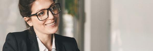 Pagos Domiciliados - Mujer con gafas y traje sonriendo y hablando con cliente
