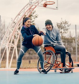 inclusion-atleta-en-silla-de-ruredas-feliz-y-su-amiga-pasandolo-bien-mientras-juegan-al-baloncesto-en-la-calle